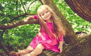 crianca de vestido rosa em cima de arvore